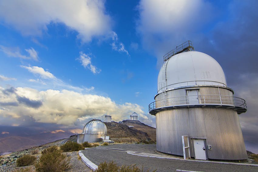 Varios observatorios abovedados alineados en lo alto de una cresta en un paisaje desértico