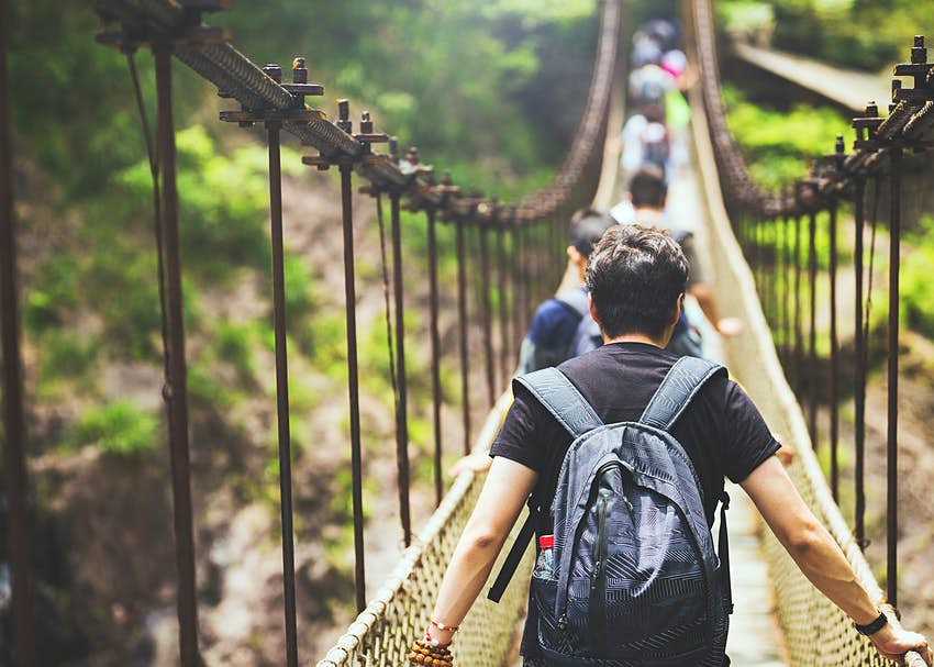 Un grupo de pasajeros camina sobre un puente colgante en la jungla © Qi Yang / Getty Images