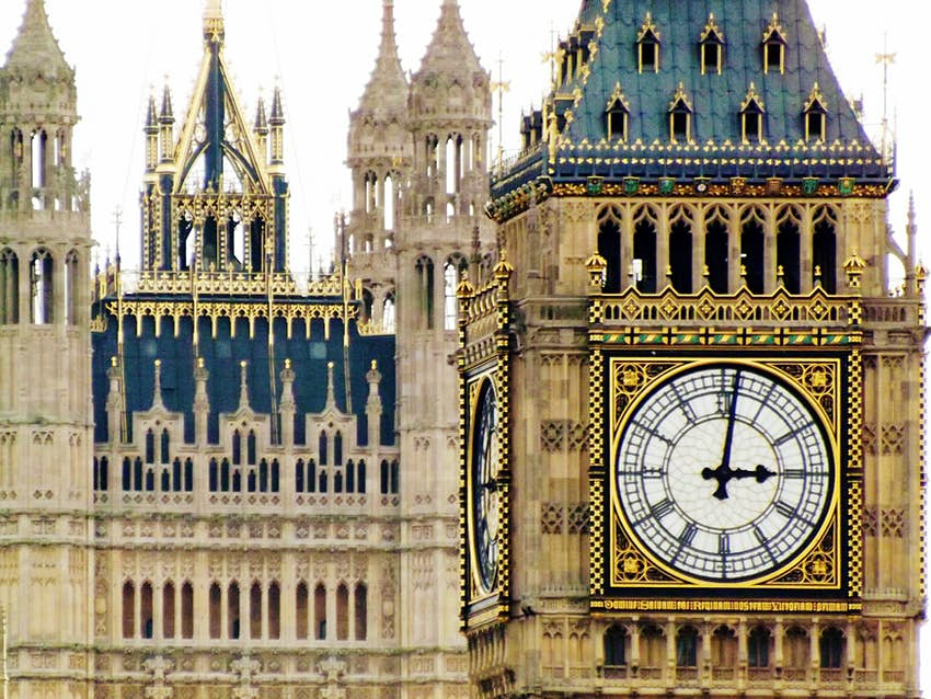 Primer plano de un enorme reloj blanco con números negros en una torre neogótica