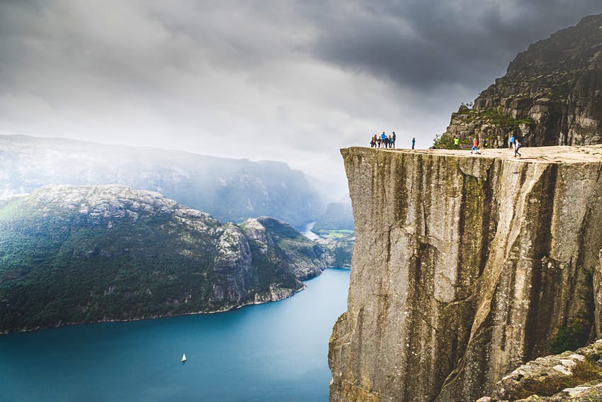 La gente camina en Prekestolen, un famoso monumento natural en Noruega.  Lysefjorden y montañas al fondo.