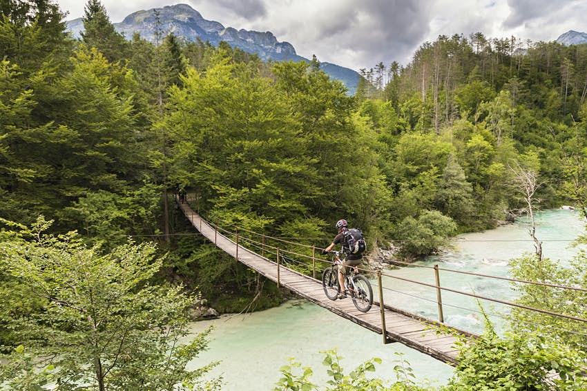 Un ciclista de montaña cruza un puente colgante en Eslovenia.