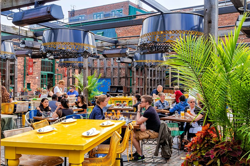 Los turistas beben en un bar al aire libre en la destilería de Toronto