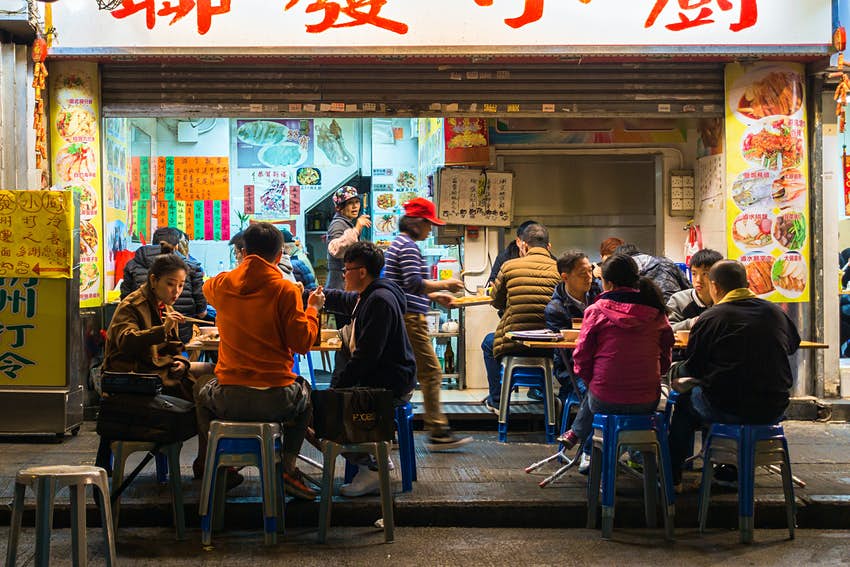 La gente come en un café en la calle en Hong Kong