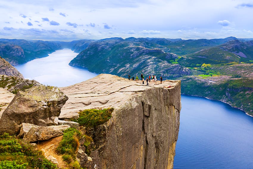 Preikestolen en el fiordo Lysefjord: una gran plataforma rocosa que sobresale de una roca en Noruega.  La gente se para en la roca para contemplar la vista del gran lago que se encuentra debajo.