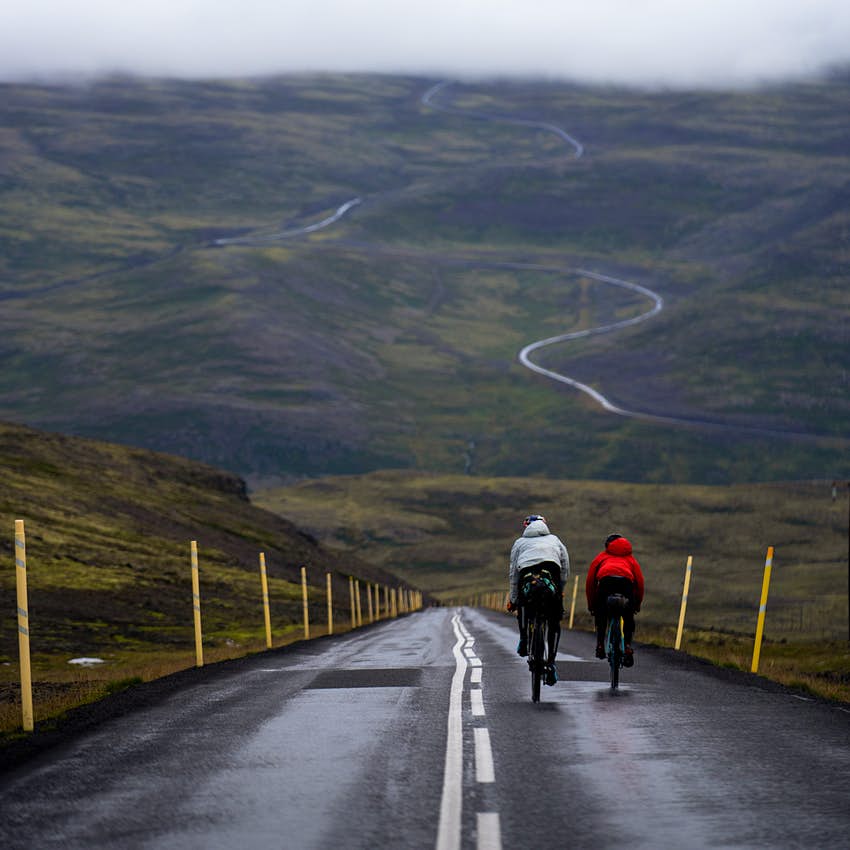 El grupo de bicicletas sube una gran colina con una vista increíble de los caminos sinuosos frente a ellos.